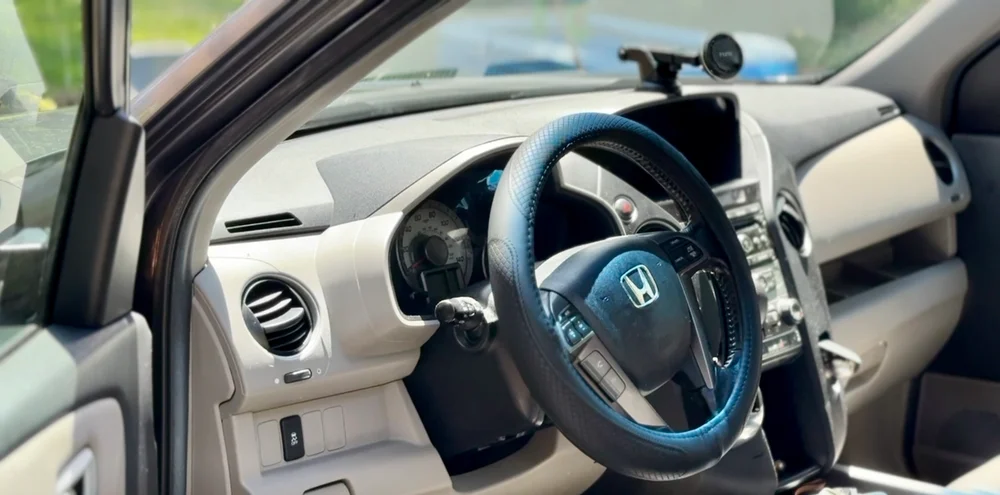 Sunlit Honda steering wheel and dashboard photographed through an open door