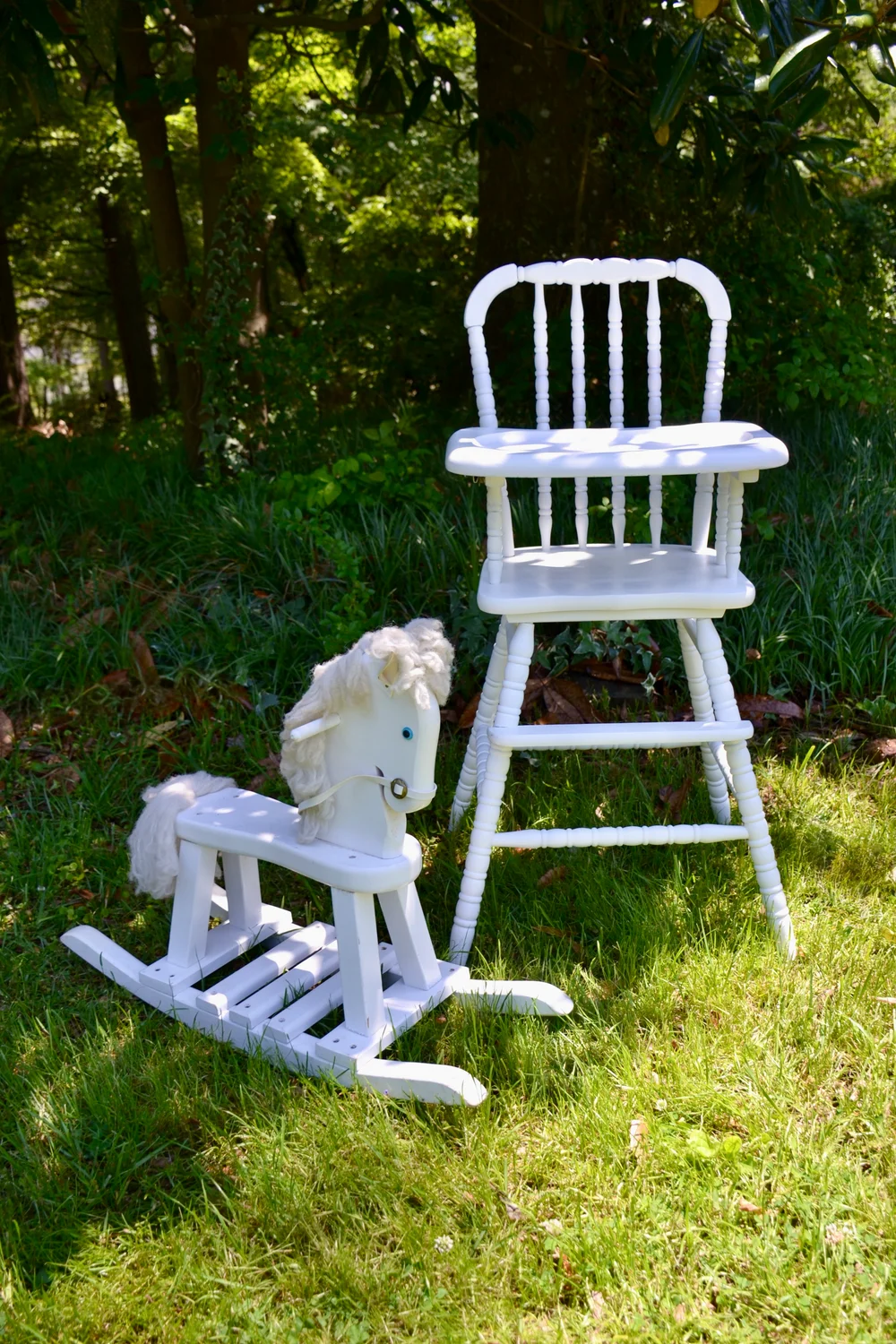 White wooden rocking horse and vintage high chair photographed outdoors
